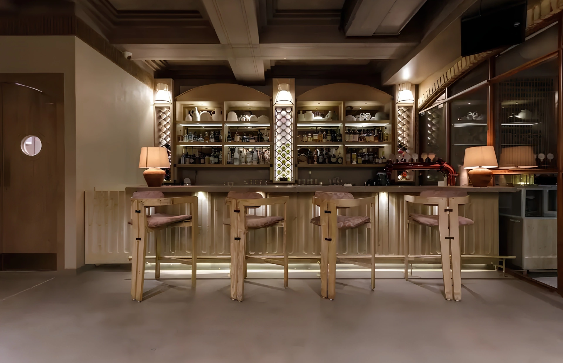 Seamless grey flooring in a warmly lit bar with timber shelving and brass stools