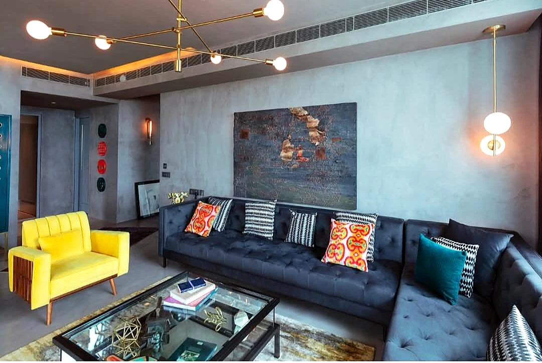 Living room with blue-grey textured walls, a dark sofa and a yellow accent chair