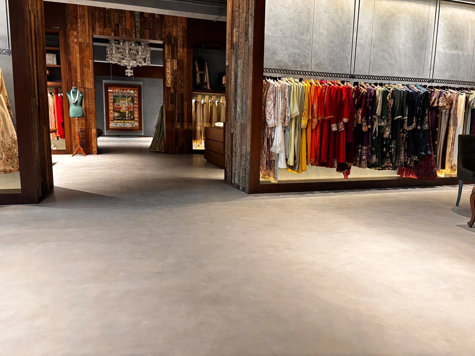 Dress boutique with seamless grey flooring, carved timber doorways and colourful clothing displays