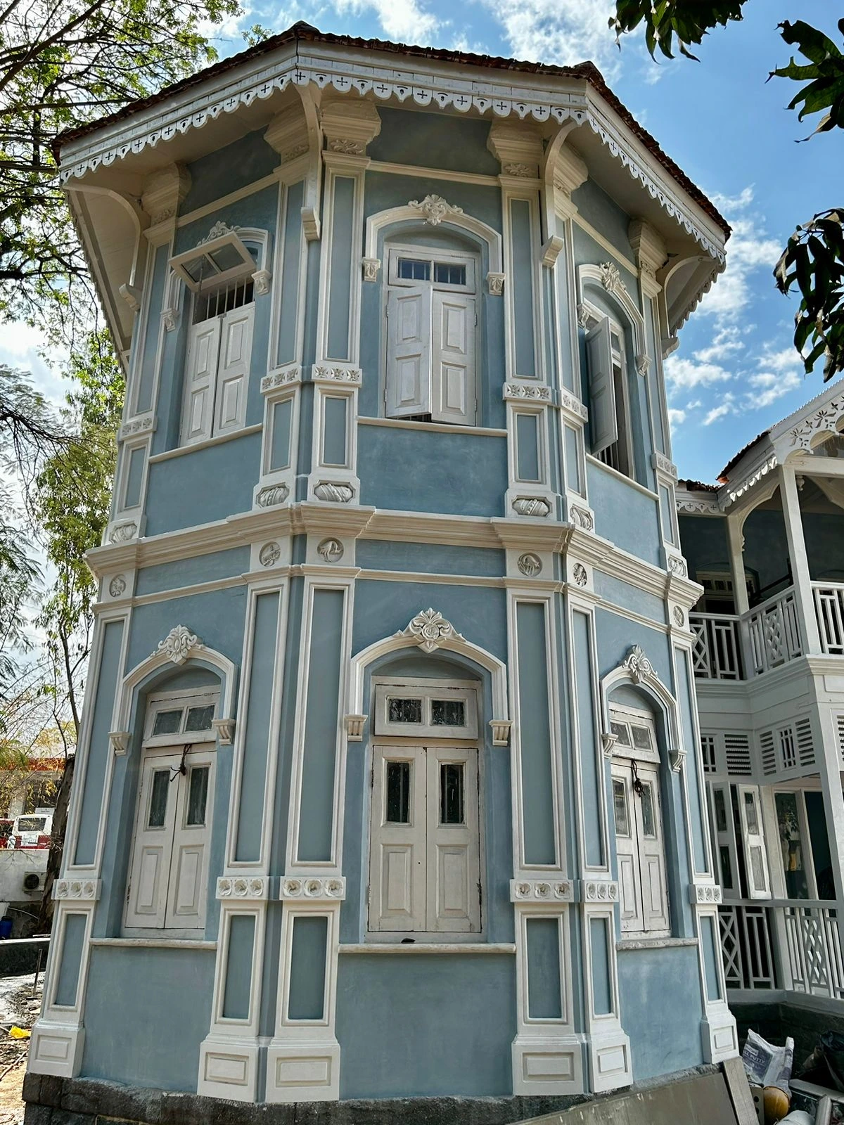 Blue villa facade with white ornamental mouldings, shuttered windows and a tiled roof