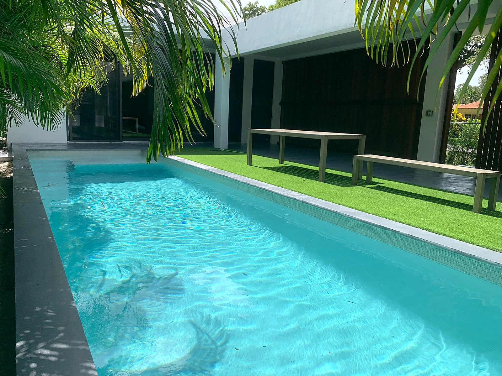 Outdoor swimming pool beside a garden terrace with tropical planting