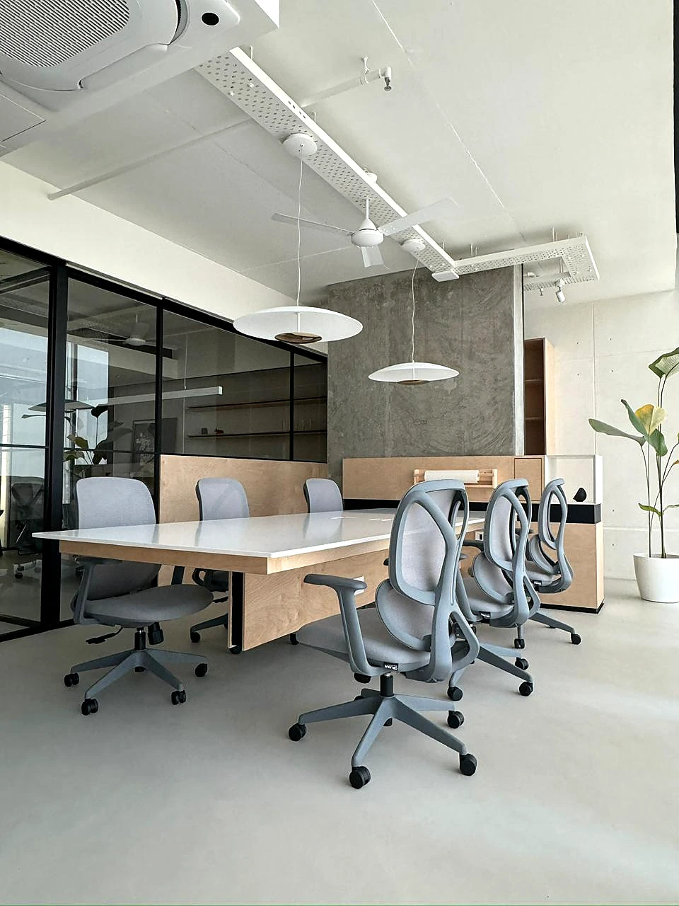 Open office with continuous grey flooring, shared desks and glass partitions