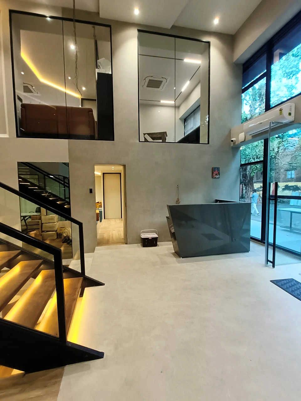 Double-height interior with grey mineral walls and an illuminated staircase