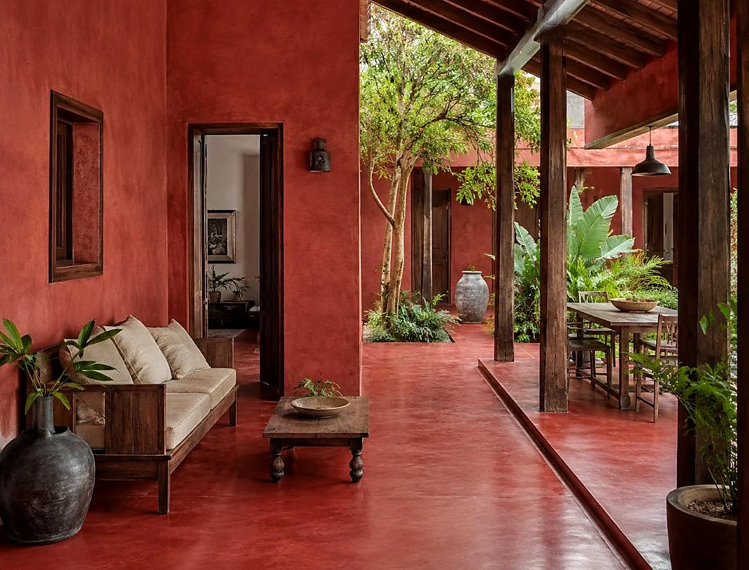 Red mineral-finish walls and flooring around a courtyard with tropical planting