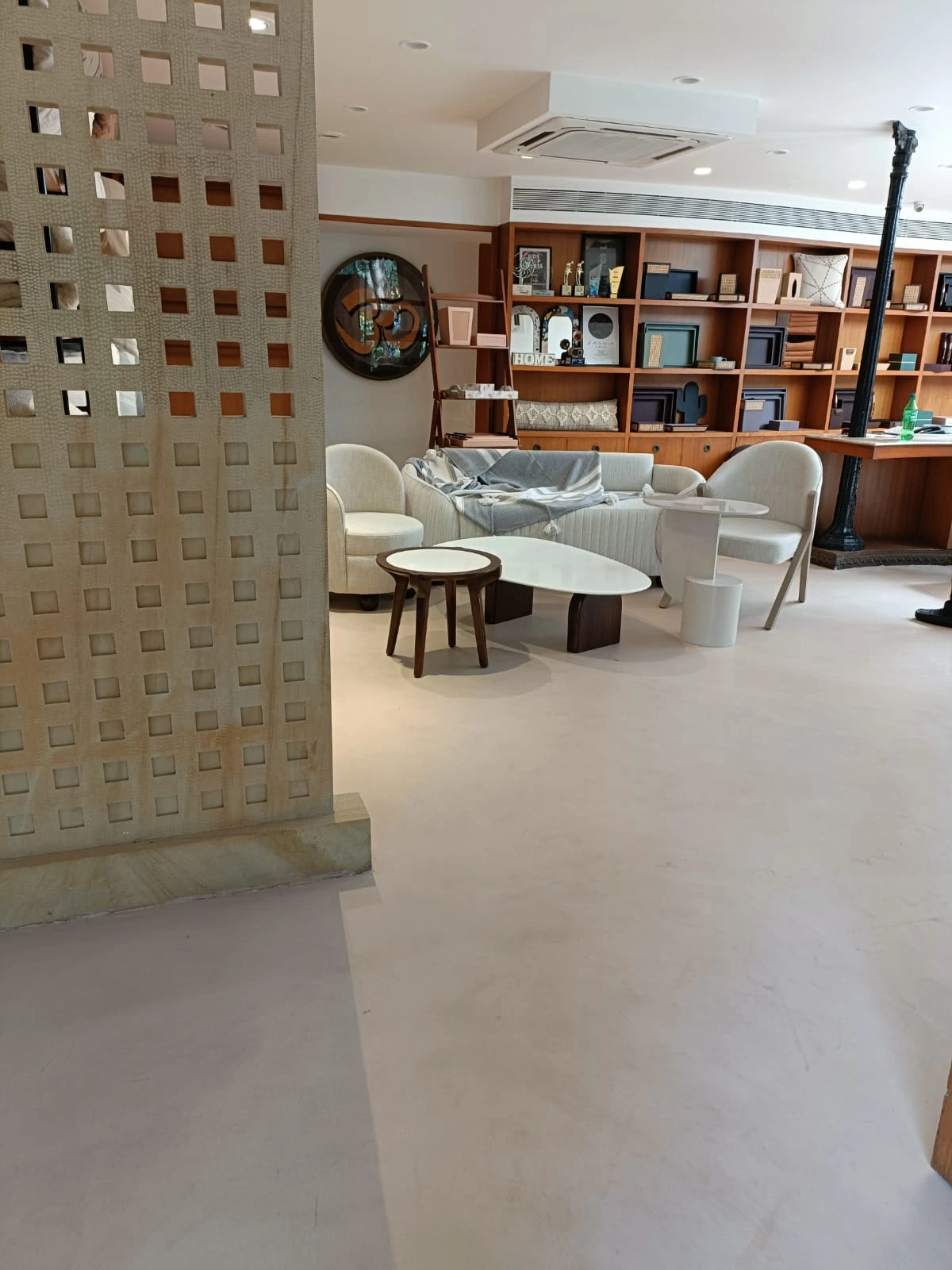 Finished pale seamless microtopping floor around lounge seating and a textured display partition in a showroom