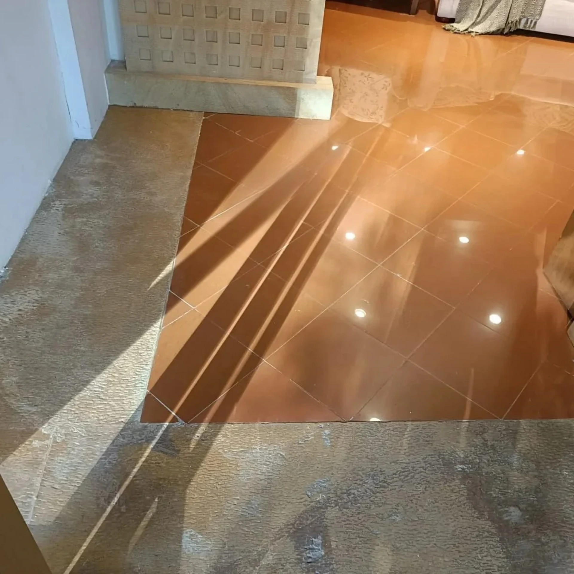 Orange tiled floor with visible grout lines and a stone border before microtopping application